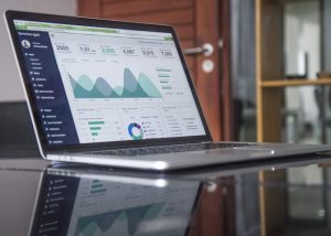 Laptop mostrando gráficos y estadísticas de análisis de datos en un entorno de oficina.